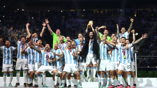 Jugadores de la Selección Argentina celebran el título mundial sosteniendo la Copa del Mundo en el Estadio de Lusail, Qatar.