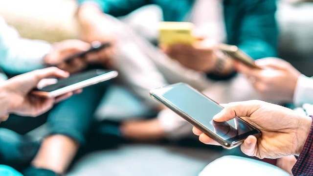 Personas realizando una transferencia de dinero acercando sus teléfonos celulares.