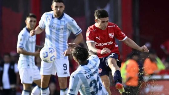 Los escudos de Independiente y Racing Club, enfrentados, sobre un fondo que representa un campo de fútbol.