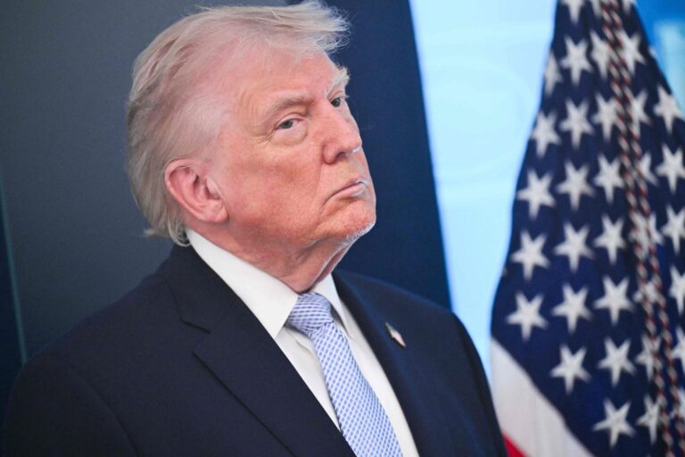 Donald Trump hablando en un podio con la bandera de Estados Unidos de fondo.