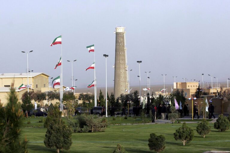 Bandera de Estados Unidos y bandera de Irán con símbolo de negociación nuclear de fondo.