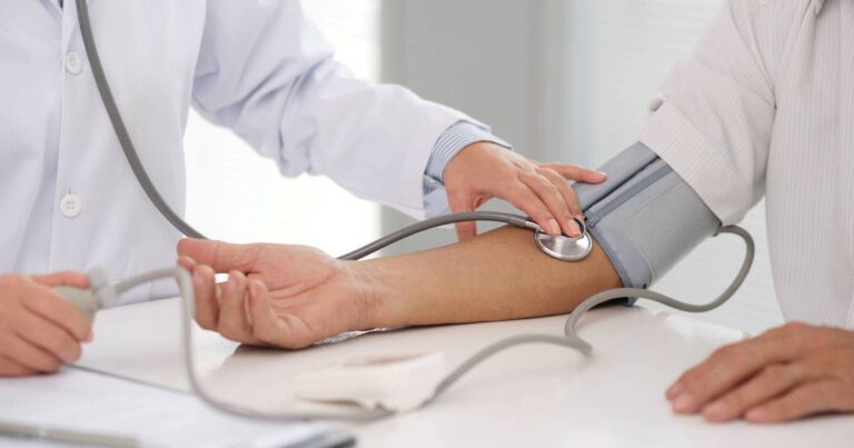 Gráfico médico mostrando medición de presión arterial junto a frascos de suplementos