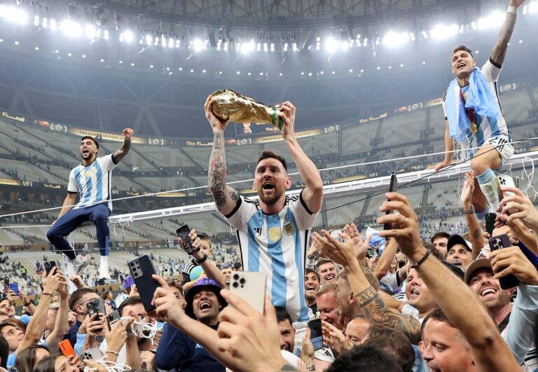 Grupo de aficionados argentinos con banderas en una calle, representando el fervor futbolero.