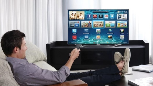 Persona usando control remoto frente a un televisor inteligente con íconos de seguridad y privacidad en pantalla.