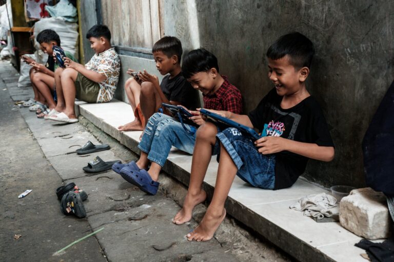 Niños utilizando smartphones y tablets en un callejón de Jakarta, Indonesia, antes de la entrada en vigor de la nueva ley de restricciones digitales.