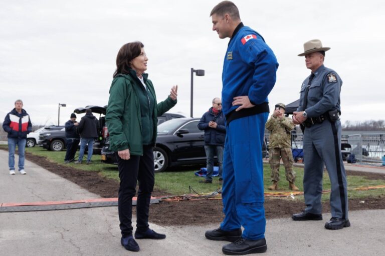 La gobernadora Kathy Hochul habla públicamente, con gráficos de la misión Artemis II de fondo.