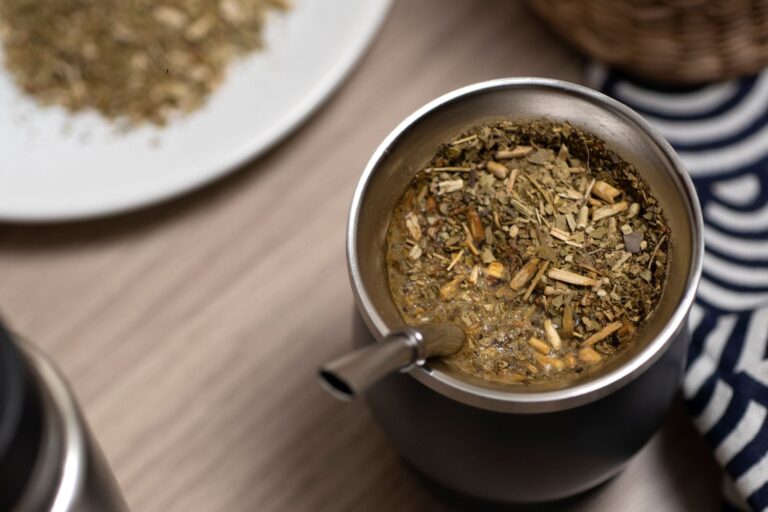 Mate argentino con hojas de menta fresca, sobre una mesa de madera.
