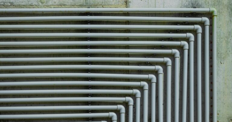 Estantería moderna construida con caños de PVC reciclados y estantes de madera, en un ambiente del hogar.