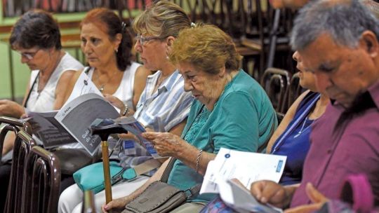 Persona mayor consultando su recibo de sueldo en una computadora con el logo de ANSES