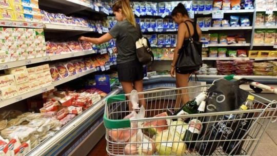 Persona comprando en supermercado con cartel de descuento