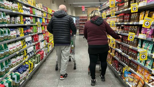 Persona haciendo compras en un supermercado con promociones visibles