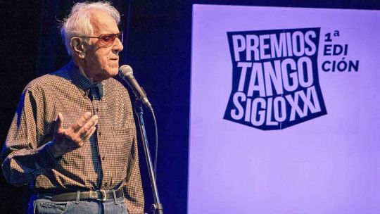 Músicos de tango tocando en un escenario con luces tenues