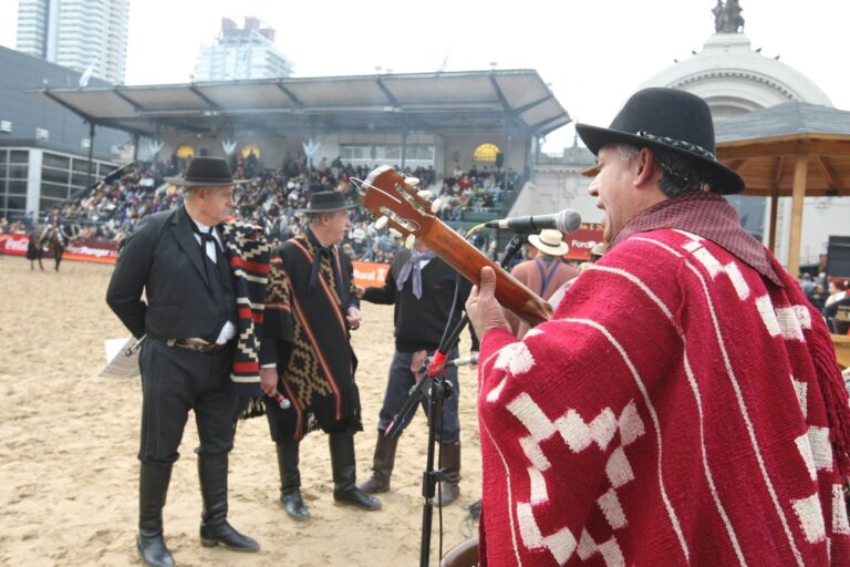 Dos payadores con guitarras frente a frente en un escenario rural