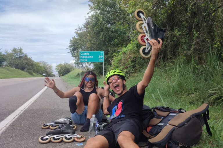 Pareja de mochileros colombianos patinando en una ruta de Sudamérica con mochilas