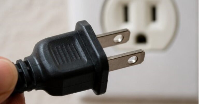 Persona ajustando tornillos de un enchufe suelto en la pared
