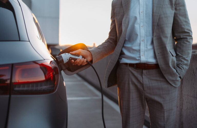 Auto eléctrico conectado a un cargador en la vía pública