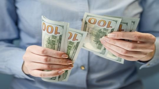 Billetes de dólar sobre una mesa con fondo de gráfico de cotizaciones