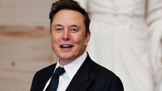 Fotografía de Elon Musk sonriendo con un traje formal