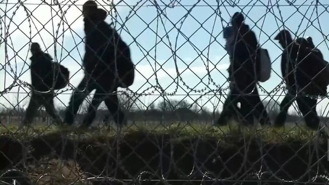 Personas en fila frente a una oficina de trámites migratorios en España