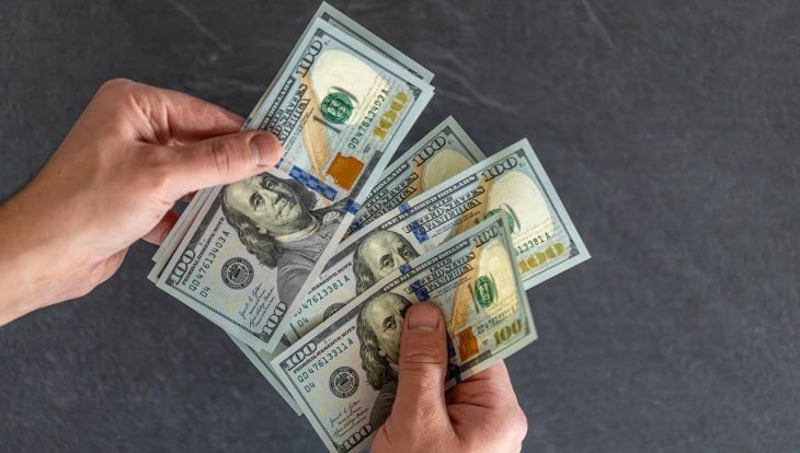 Sobres de papel con dinero y una alcancía sobre una mesa de madera
