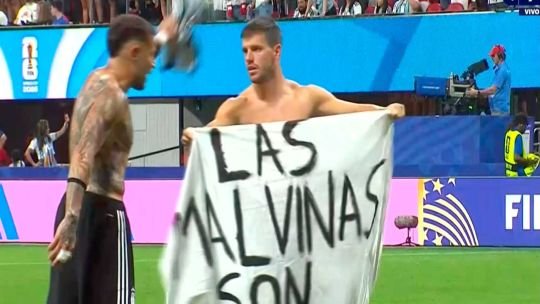 Futbolistas argentinos sostienen una bandera con la leyenda Las Malvinas son argentinas en el campo de juego